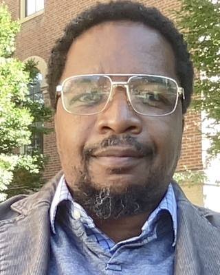 Kevin N. Hall, seated outdoors in front of a brick campus building at the University of Illinois.